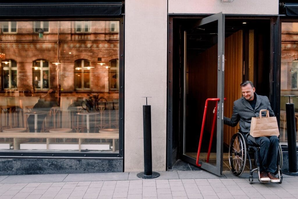 A man in a wheelchair is standing outside of a building.
