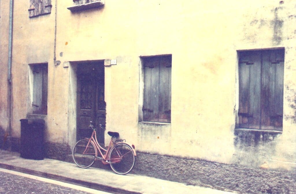 Bike parked against a wall with a door and three windows