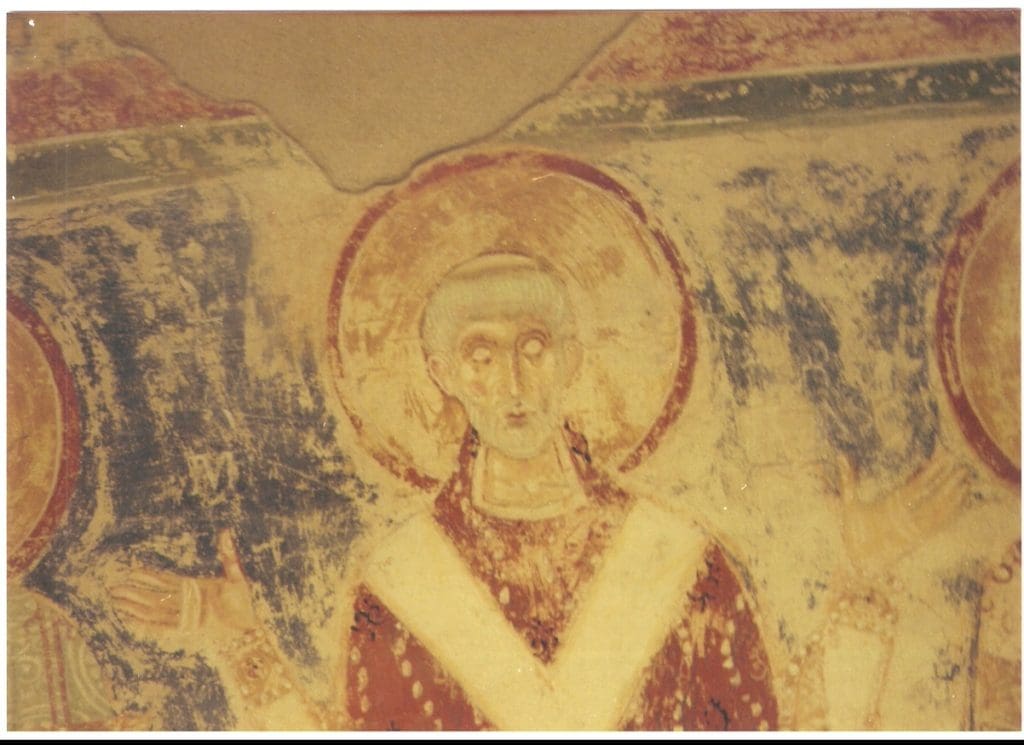 Byzantine-era fresco depicting a saint with a halo in a red robe with outstretched arms, inspired by Donnellan's diaries.
