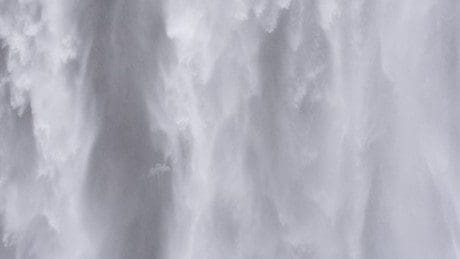 A white waterfall with water pouring down it.