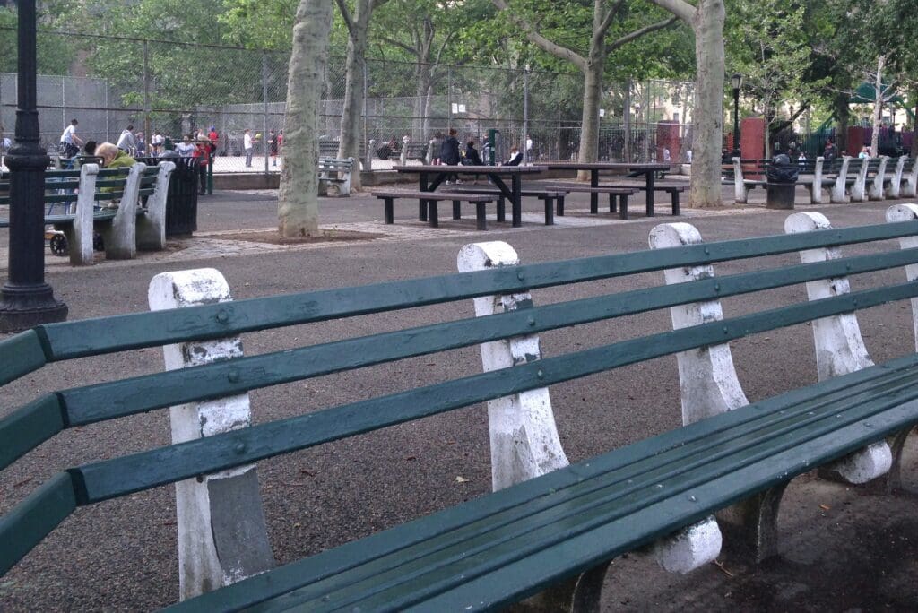 A park bench with benches and trees in the background.