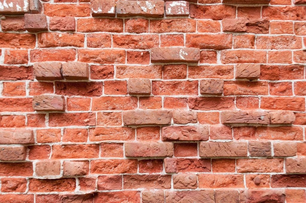 Close-up of a worn red brick wall with visible mortar.